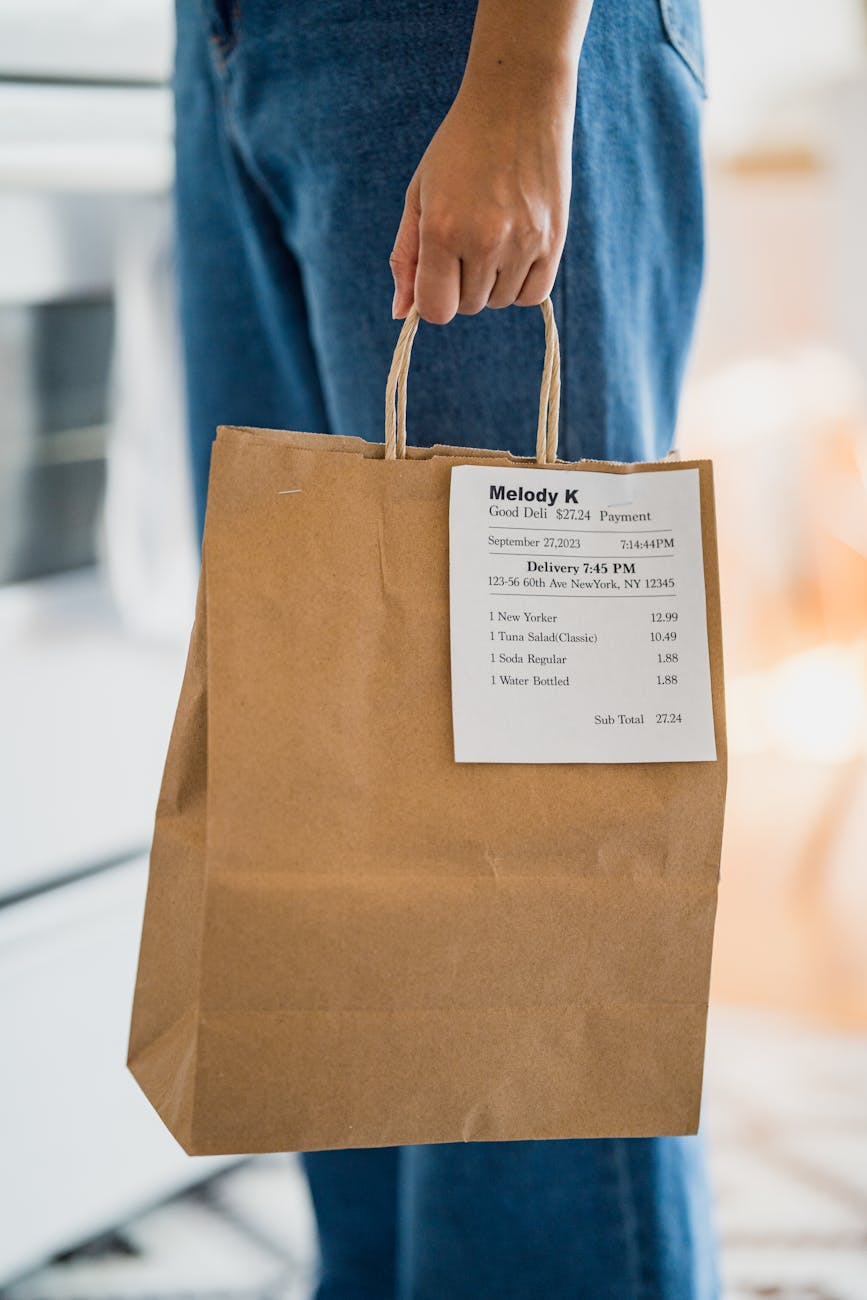 close up of a person holding a food delivery in a paper bag